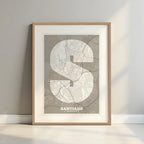 Framed Santiago de Compostela in Super Bold design, a typographic poster where the city map is overlaid with extra-thick lettering for a modern, high-impact look designed in light brown and an off-white background with a white margin border in a warm lit minimalist setting