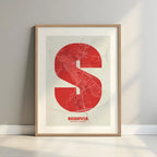 Framed Segovia in Super Bold design, a typographic poster where the city map is overlaid with extra-thick lettering for a modern, high-impact look designed in red and an off-white background with a white margin border in a warm lit minimalist setting