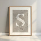 Framed Segovia in Classic design, inspired by chiseled typography with an elegant font that creates a beautiful visual contrast designed in light brown and an off-white background with a white margin border in a warm lit minimalist setting
