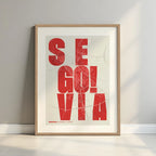 Framed Segovia in Unruled design, where the city name letters appear randomly across different lines for a truly original urban layout designed in red and an off-white background with a white margin border in a warm lit minimalist setting