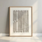 Framed Segovia in Extra Compressed design, where the letters are tightly squeezed to fit the city's map shape designed in light brown and an off-white background with a white margin border in a warm lit minimalist setting