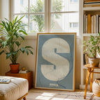 Diseño de interiores moderno con la lámina de Soria en mi diseño la Súper Bold, un póster tipográfico donde el mapa de la ciudad se fusiona con una tipografía extra gruesa para un impacto visual moderno diseñado en gris azulado y fondo blanco roto, expuesto en la pared de un salón