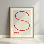 Framed Soria in Ultralight design, a minimalist aesthetic combining urban cartography with modern, extra-thin elegant lettering designed in red and an off-white background with a white margin border in a warm lit minimalist setting