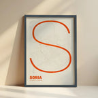 Framed Soria in Ultralight design, a minimalist aesthetic combining urban cartography with modern, extra-thin elegant lettering designed in orange and an off-white background with no border edge-to-edge print leaning against a wall