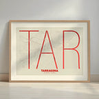 Framed Tarragona in Ultralight design, a minimalist aesthetic combining urban cartography with modern, extra-thin elegant lettering designed in red and an off-white background with a white margin border in a warm lit minimalist setting
