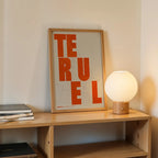 Modern interior design with a Teruel in Unruled design, where the city name letters appear randomly across different lines for a truly original urban layout designed in orange and an off-white background, displayed on a living room wall