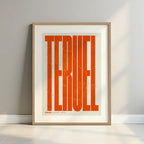 Framed Teruel in Extra Compressed design, where the letters are tightly squeezed to fit the city's map shape designed in orange and an off-white background with a white margin border in a warm lit minimalist setting