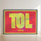 Framed Toledo in Super Bold design, a typographic poster where the city map is overlaid with extra-thick lettering for a modern, high-impact look designed in yellow and fuchsia with no border edge-to-edge print leaning against a wall