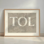 Framed Toledo in Classic design, inspired by chiseled typography with an elegant font that creates a beautiful visual contrast designed in light brown and an off-white background with a white margin border in a warm lit minimalist setting