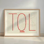 Framed Toledo in Ultralight design, a minimalist aesthetic combining urban cartography with modern, extra-thin elegant lettering designed in red and an off-white background with a white margin border in a warm lit minimalist setting