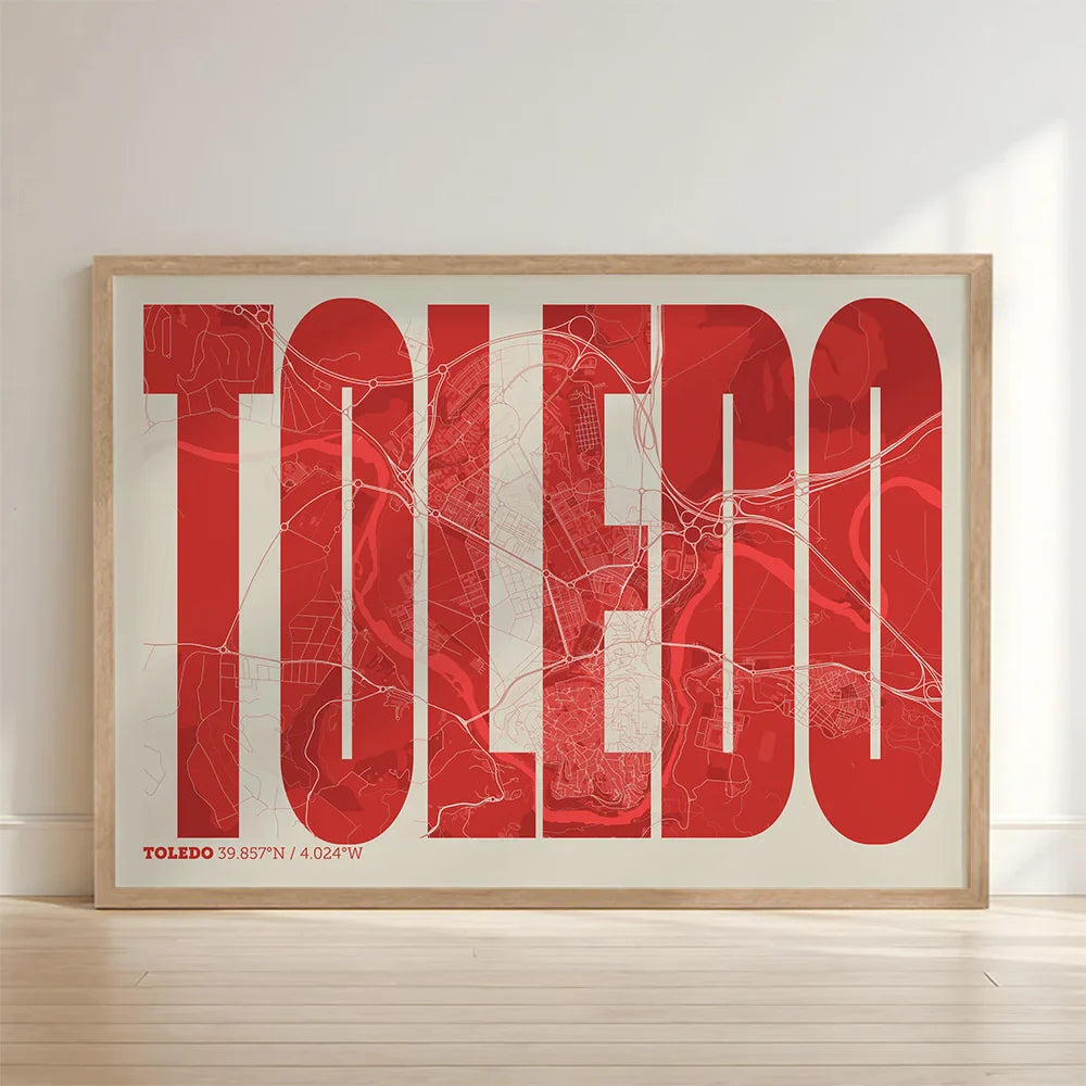 Framed Toledo in Extra Compressed design, where the letters are tightly squeezed to fit the city's map shape designed in red and an off-white background with no border edge-to-edge print leaning against a wall