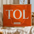 Diseño de interiores moderno con la lámina de Toledo en el diseño la Clásica, inspirado en la tipografía cincelada con una fuente elegante que crea un bonito contraste visual diseñado en naranja y fondo blanco roto, expuesto en la pared de un salón