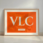 Framed Valencia in Classic design, inspired by chiseled typography with an elegant font that creates a beautiful visual contrast designed in orange and an off-white background with a white margin border in a warm lit minimalist setting