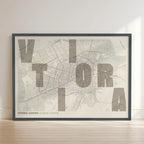 Framed Vitoria-Gasteiz in Unruled design, where the city name letters appear randomly across different lines for a truly original urban layout designed in light brown and an off-white background with no border edge-to-edge print leaning against a wall