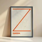 Framed Zamora in Ultralight design, a minimalist aesthetic combining urban cartography with modern, extra-thin elegant lettering designed in orange and an off-white background with no border edge-to-edge print leaning against a wall