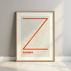 Framed Zamora in Ultralight design, a minimalist aesthetic combining urban cartography with modern, extra-thin elegant lettering designed in orange and an off-white background with a white margin border in a warm lit minimalist setting