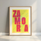 Framed Zamora in Unruled design, where the city name letters appear randomly across different lines for a truly original urban layout designed in yellow and fuchsia with a white margin border in a warm lit minimalist setting